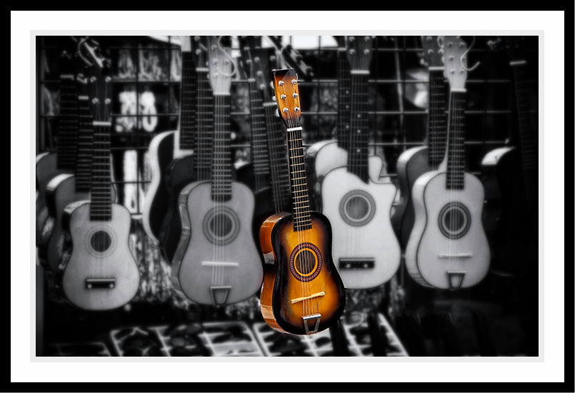 One guitar in color among black and white guitars.